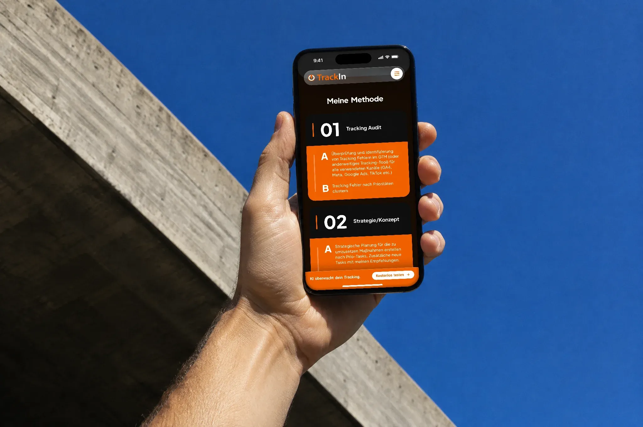 Eine Hand hält ein Handy mit der Website von TrackIn vor einen tiefblauen Himmel, daneben die Kante eines Betondachs