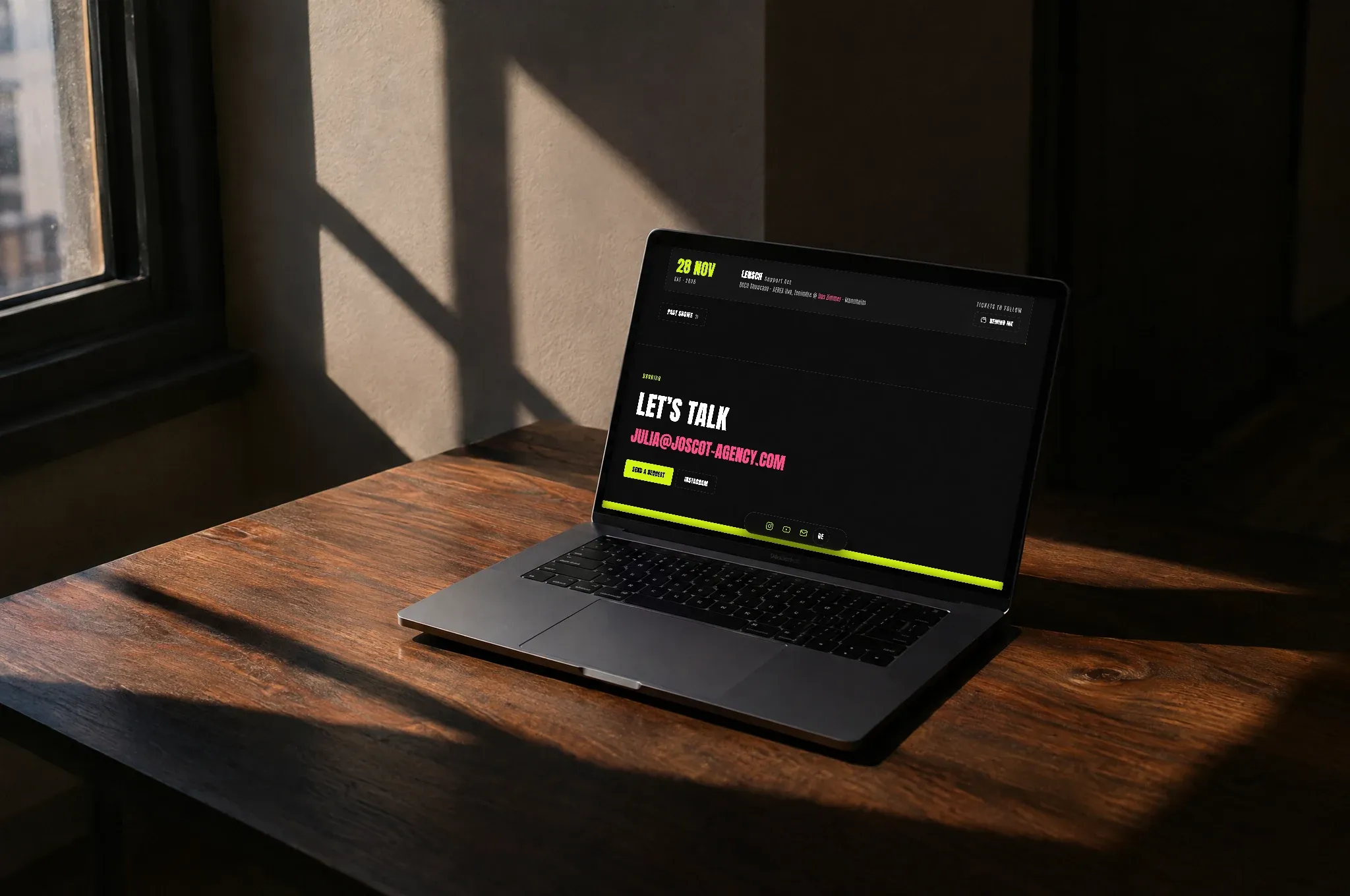 Ein Laptop auf einem Holztisch zeigt Showkalender und Buchungsanfrage der Joscot-Website in den Markenfarben