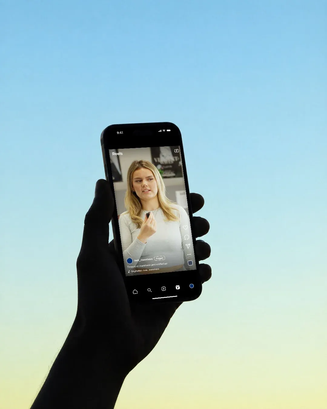 Eine Hand hält ein Handy gegen den blauen Himmel, darauf ein Reel der Handwerkskammer Mannheim