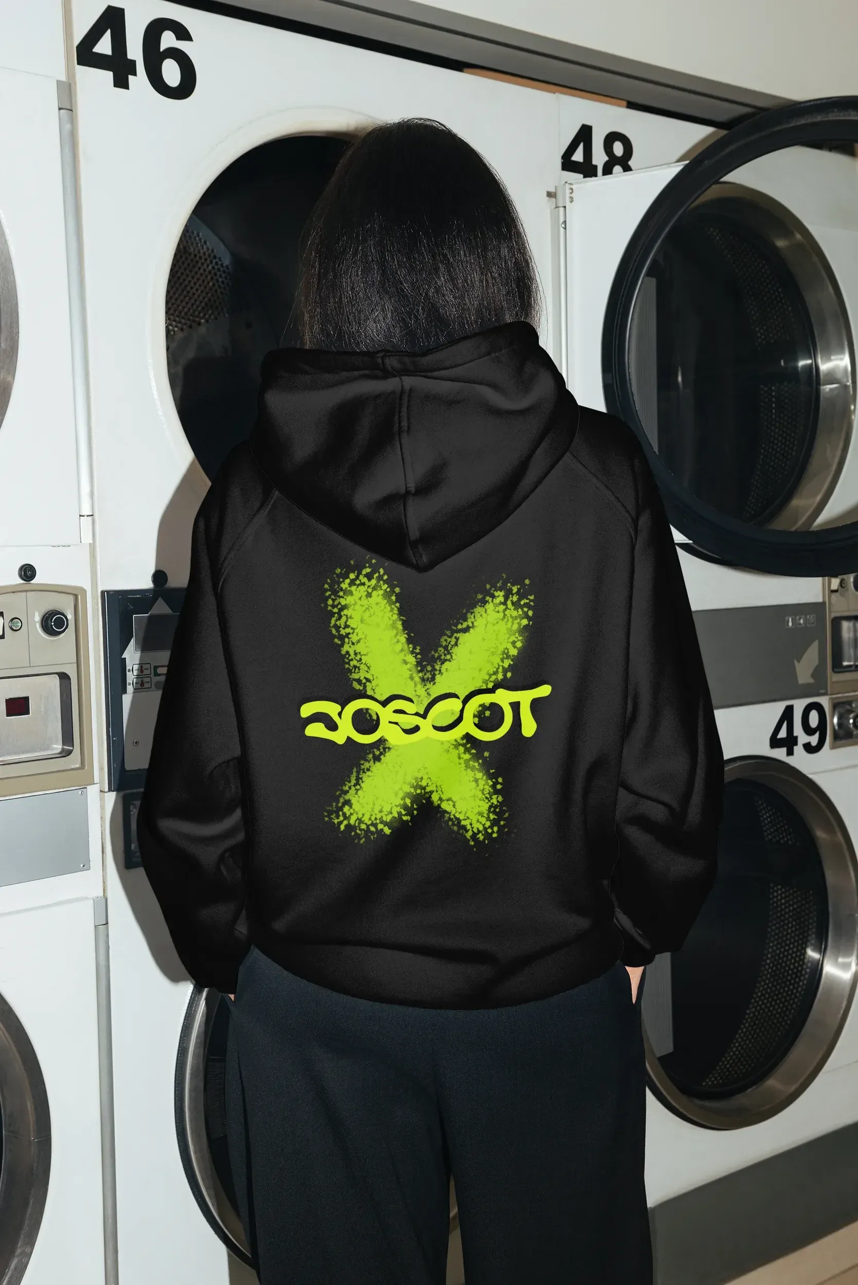 Schwarzer Hoodie mit dem Joscot-Logo auf dem Rücken, vor einer Reihe Waschmaschinen