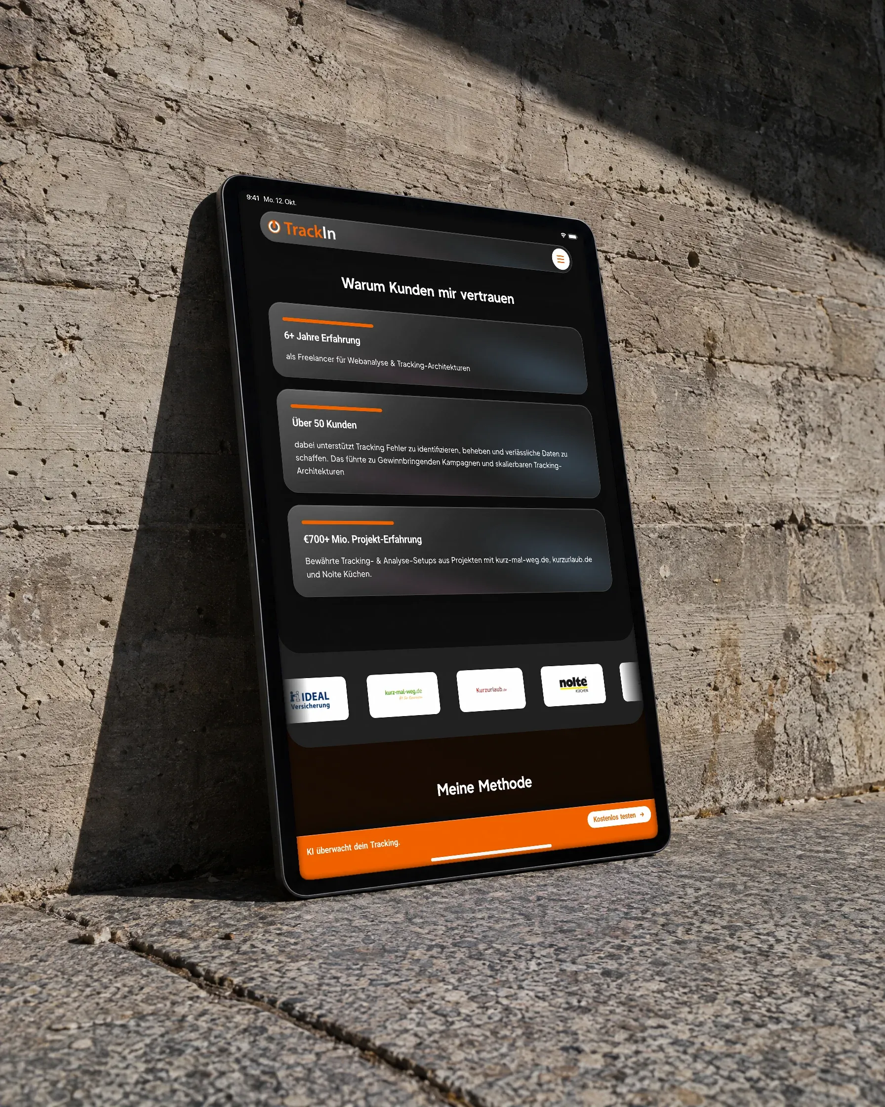 Ein Tablet mit der Website von TrackIn lehnt an einer Sichtbetonwand und wirft einen scharfen Schatten