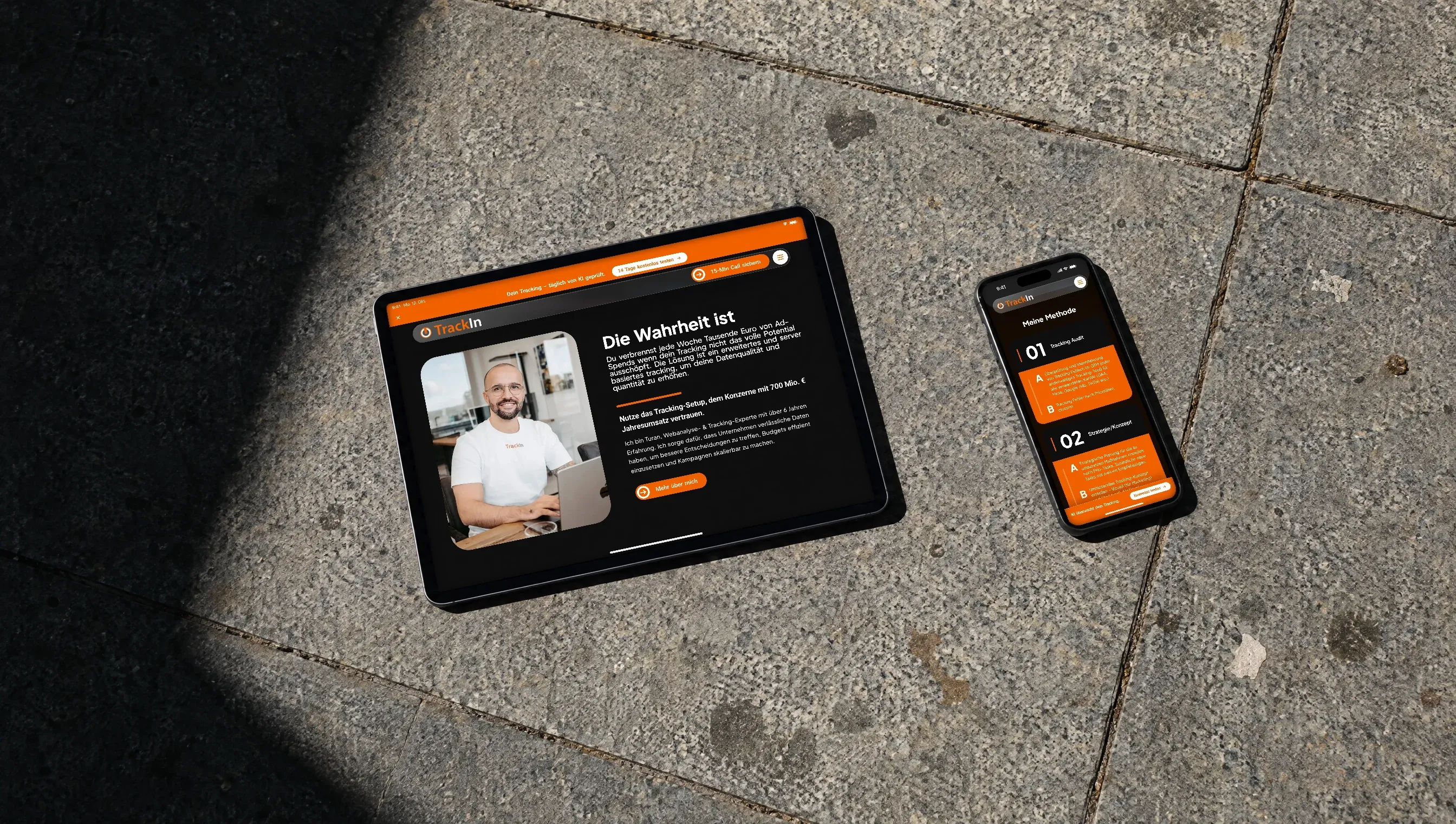 Ein Tablet und ein Handy liegen nebeneinander auf Granitplatten in der Sonne, auf beiden die Website von TrackIn