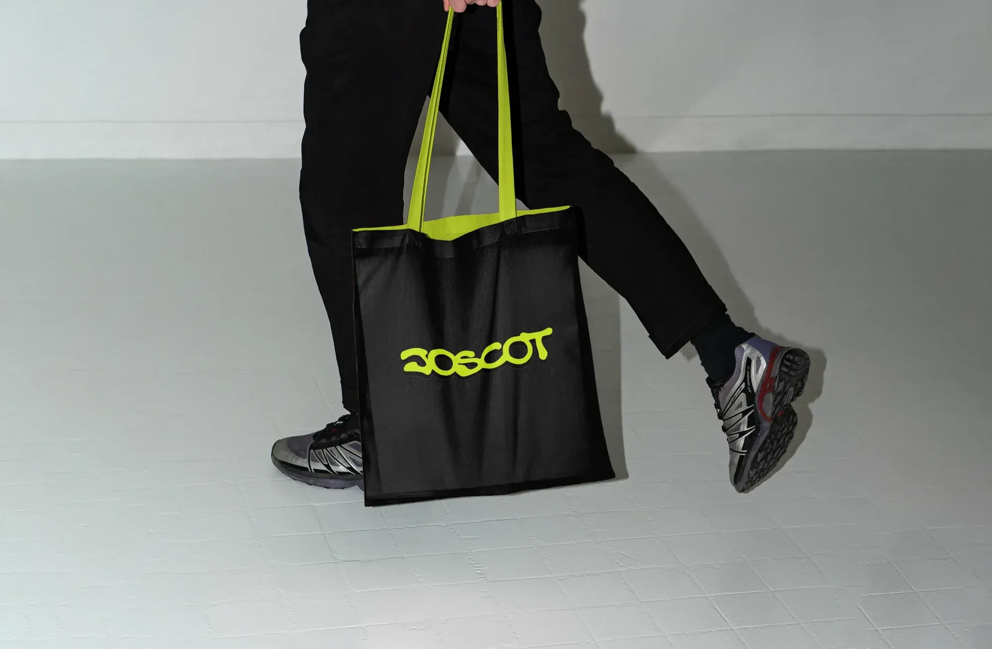Schwarze Stofftasche mit Joscot-Logo, getragen im Gehen