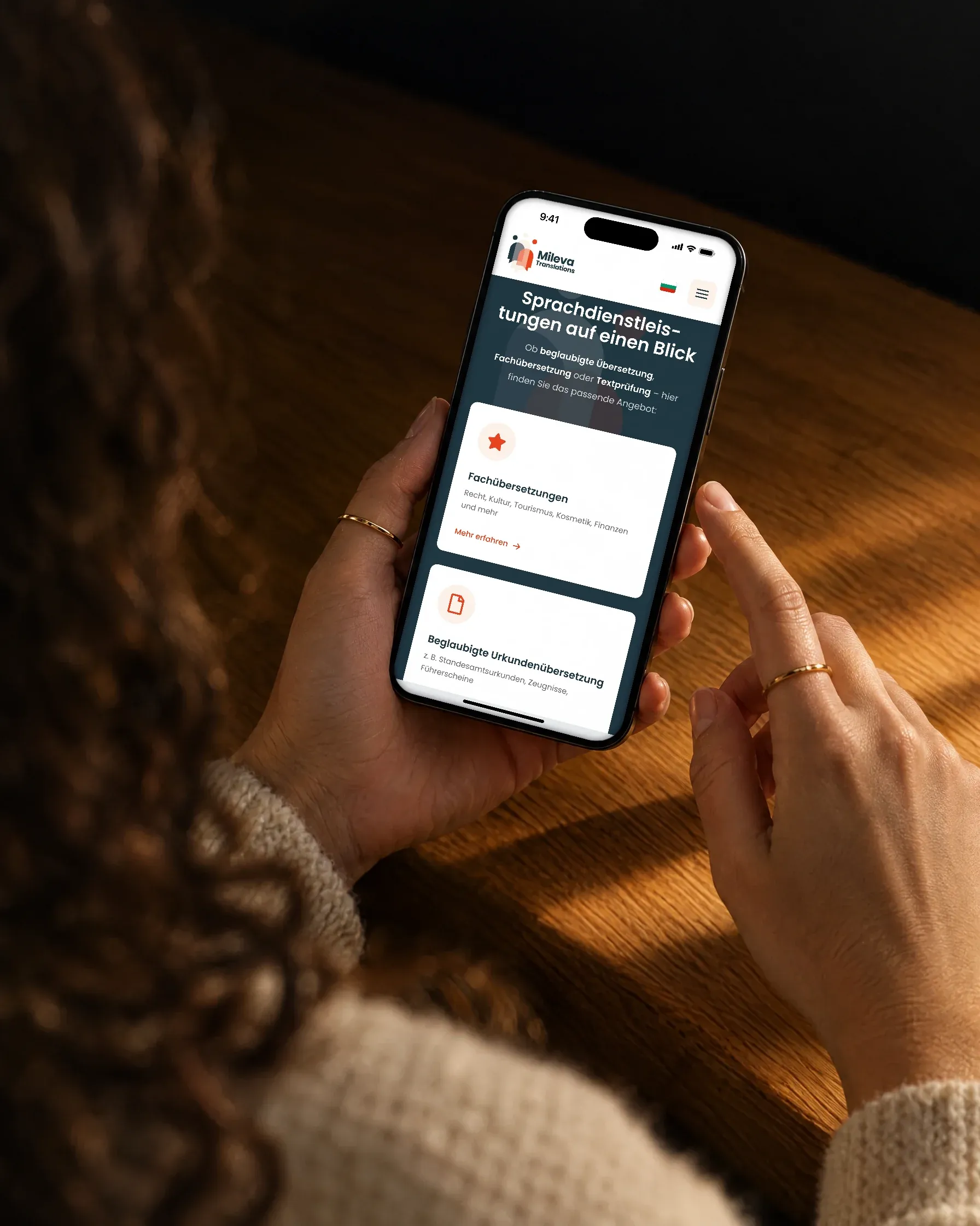 Zwei Hände halten ein Handy, auf dem die Sprachdienstleistungen von Mileva Translations als Karten zu sehen sind
