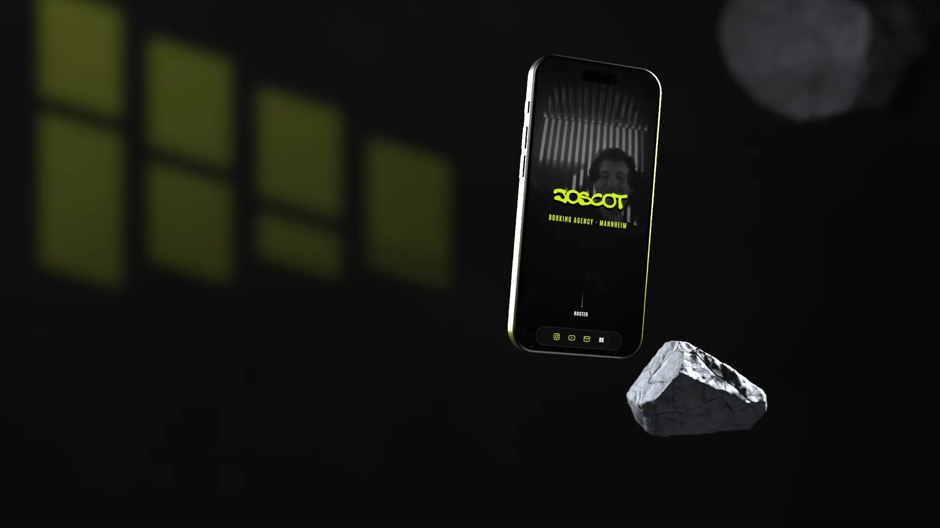 Ein Handy schwebt vor einer dunklen Wand neben einem Stein, darauf wird die Website von Joscot durchgescrollt