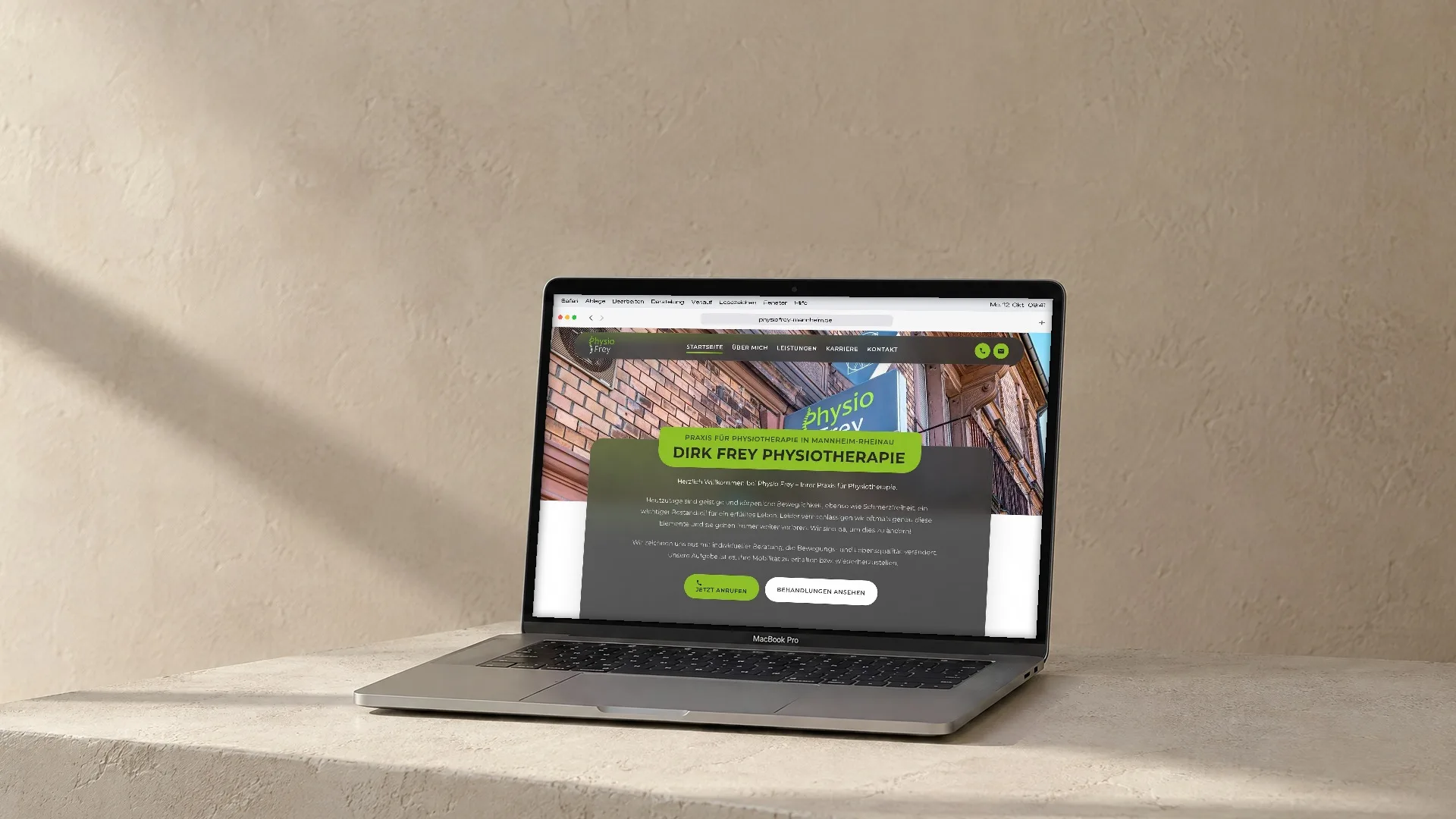 Ein Laptop steht auf einem weissen Putzsockel vor einer hellen Kalkwand im Nachmittagslicht, auf dem Bildschirm läuft die Website von Physio Frey durch